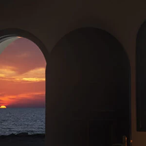 View Of A Colourful, Dramatic Sunset Over The Ocean Through An Arched Doorway; Paphos, Cyprus
