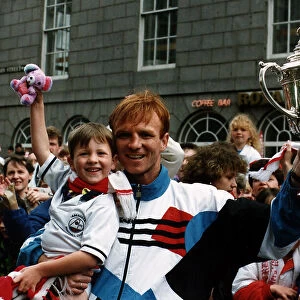 Alex McLeish of Aberdeen Football Club in the street holding up his son in one hand
