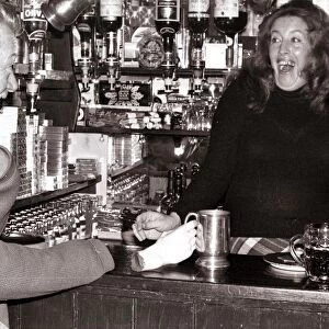 A barmaid at the Red Lion Pub in Kings Langley, Hertfordshire laughing after customer