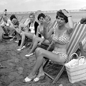 Beauty contest girls sitting in deck-chairs on the beach at Skegness putting on their