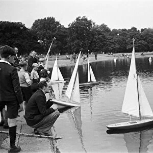 Children and adults sailing their toy yachts on the Round Pond in Kensington Gardens