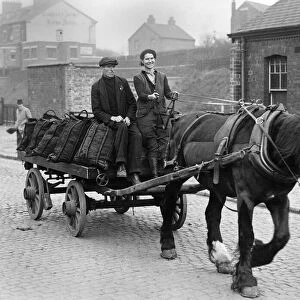 Coal Women. Woman on a cart laiden with sacks of coal, being pulled along by a horse