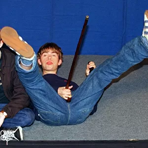 Damon Albarn lead singer of the pop group Blur lying on the floor holding a walking stick