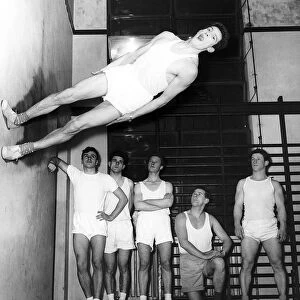 Gymnast Ken Popplewell walking on a wall watched by other members of the Ilford gymnastic