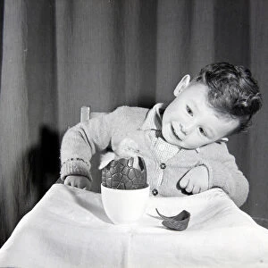 Little boy with chick in chocolate Easter egg. Circa 1960