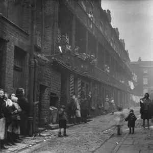 People standing between two terraces in a slum housing area of Liverpool. 2nd March, 1933