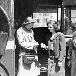 Picture shows a female bus conductor in World War Two. She issues a young girl with