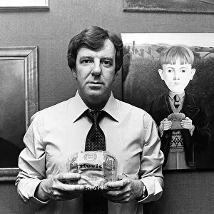 Russell Harty, television presenter at home. He is holding a loaf of Hovis Bread