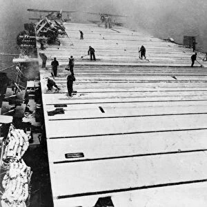 Sweeping the snow covered flight deck of the British escort carrier HMS Fencer during a