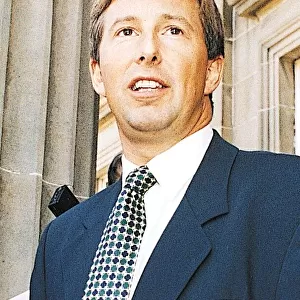 TV presenter Bill McFarlan wearing blue suit and green and blue spotted tie