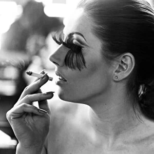 A woman wearing the longest eye lashes in the world, smoking a cigarette