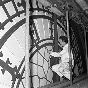 A workmen inspects the minute hand of the clock face of Big Ben during the major overhaul