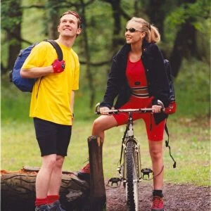 A young couple enjoy a romantic day out in the countryside hiking and cycling