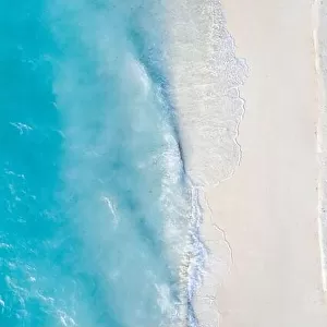Aerial view of sandy beach and ocean with waves. Beautiful tropical white empty beach and sea waves seen from above. Beautiful sea landscape beach