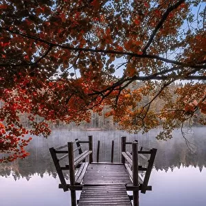 Beautiful fall colors with wooden pier and peaceful lake at autumn morning in Finland