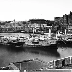 View of the Porto Militare in Naples, where many merchant ships are docked. Some buildings and civilian homes are visible in the background