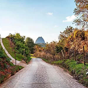 Colombia, Antioquia, Rural road with view of Penon de Guatape Rock