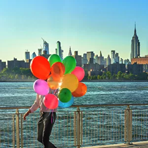 New York City, Brooklyn, Williamsburg, man with balloons walking along the promenade at Domino Park