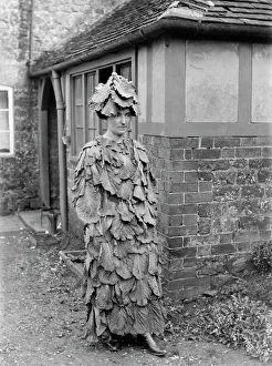 <b class=qtipBold><figcaption>Cabbage leaf costume BB97_08307</figcaption></b><br>'Cabbage Lady', Hellidon, Northamptonshire. A view of a lady wearing a cabbage leaf costume outside the school house. Photographed by Alfred Newton and Son. Date range:1907-1920.<br><em>© Historic England</em> Cabbage leaf costume BB97_08307