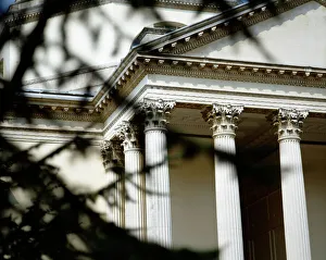 <b class=qtipBold><figcaption>Chiswick House K020290</figcaption></b><br>CHISWICK HOUSE, London. A view of part of the entrance portico seen through tree branches. Palladian style showing columns, capitals and a section of the pediment.<br><em>© Historic England</em> Chiswick House K020290