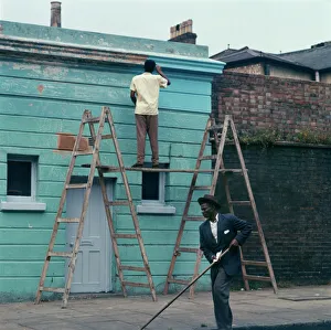 <b class=qtipBold><figcaption>Kentish Town, 1960s FF003351</figcaption></b><br>A man on stepladders re-painting the exterior of a business premises in Kentish Town, London. 1960s. Photographer, John Gay.<br><em>© Historic England Archive</em> Kentish Town, 1960s FF003351