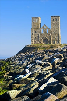 <b class=qtipBold><figcaption>Reculver Towers N100065</figcaption></b><br>RECULVER TOWERS AND ROMAN FORT, Kent. View of the twin towers with rocks of hard coastal defences in the foreground.<br><em>© Historic England</em> Reculver Towers N100065
