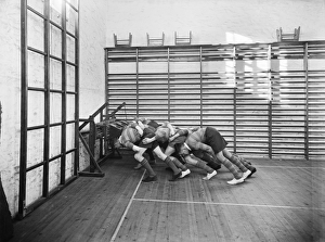 <b class=qtipBold><figcaption>Scrummaging CC46_00132</figcaption></b><br>Launceston College, Launceston, Cornwall. Students practising on a wall mounted scrummage machine in the school's gymnasium. Photographed by Marshall Keene and Company between 1931-1939.<br><em>© Historic England Archive</em> Scrummaging CC46_00132