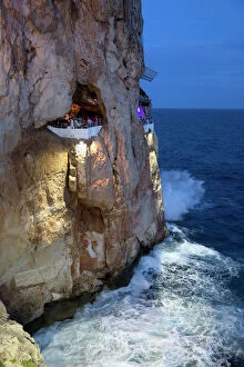 Balcony Collection: Bar built in cliff caves, Cova d en Xoroi in evening, Cala en Porter, Menorca, Balearic Islands