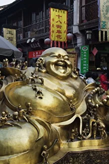 Four People Gallery: A golden statue of a reclining laughing Buddha covered in small Buddhas