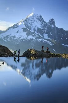 Four People Gallery: Hikers on the shores of Lac de Cheserys, with Aiguille Verte reflected at dawn, Chamonix
