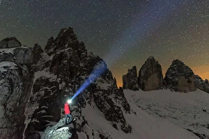 South Tyrol Collection: Man with head torch illuminates the starry sky over the snowy Paterno mountain