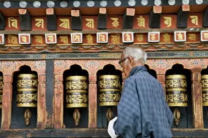 Religion & Spirituality Collection: Old Bhutanese man turning prayer wheels in Buddhist temple, Thimphu, Bhutan, Asia