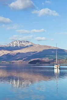 Tranquil Collection: Picturesque tranquil Loch Lomond with sailing boat, snow covered Beinn Uird behind