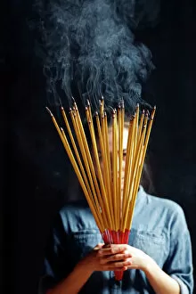Temples Gallery: Young Chinese woman praying with big burning incense sticks in her hands