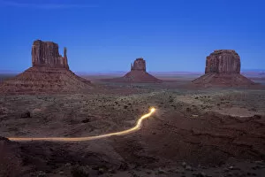 Valley Of The Rocks Collection: Light trail from car driving on scenic drive road near The Mitten Buttes in Monument