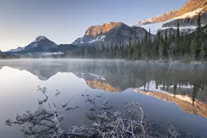Morning mist burns off the still reflective waters of Bow Lake in the Canadian Rockies