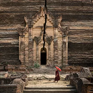 Pagoda Collection: Novice monk walking towards unfinished Pahtodawgyi pagoda known for a crack caused by a