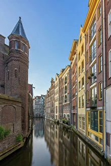 Tourist Attractions Collection: Residential buildings and houses amidst Oudezijds Achterburgwal canal against sky, De Wallen