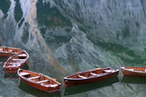 Tourist Attractions Collection: Row boats floating in the Braies lake on a calm morning, with the mountains reflecting in
