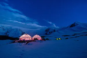 The yurts and tents of peak Lenin camp one illuminated at dusk with Peak Lenin massif in The yurts and tents of peak Lenin camp one illuminated at dusk with Peak Lenin massif in