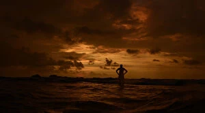 Leisure Time Collection: A man stands in the sea with his hands on his hips as he watches the sunset in Hikkaduwa