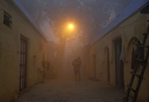 Indian Architecture Gallery: A man walks out of his house in an alley on a cold and foggy morning in New Delhi