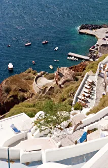 Step Gallery: Along the cliff of Oia, view the boats docked in the water, Greece