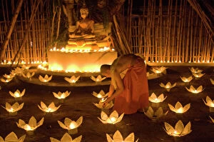 Candle Collection: Monks lighting khom loy candles and lanterns for Loi Krathong festival
