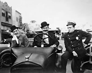 Town Gallery: LAUREL AND HARDY, 1928. Stan Laurel, left, and Oliver Hardy with a police officer in the silent film Leave Them Laughing