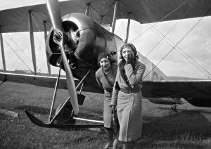 Two women in front of a biplane