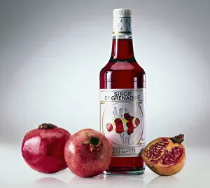 Bottle of grenadine with two-and-a-half pomegranates beside it