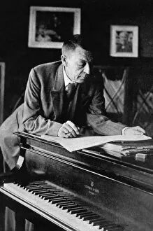 Musical Instrument Collection: Russian composer, sergei v, rachmaninov, looking over a manuscript at his piano in the late 1920s