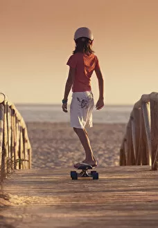 Enjoying Gallery: A Young Person Skateboarding With Bare Feet Over A Wooden Boardwalk Towards The Beach; Tarifa