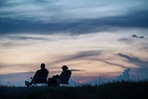 Enjoying Collection: Silhouette of couple sitting at a park at sunset